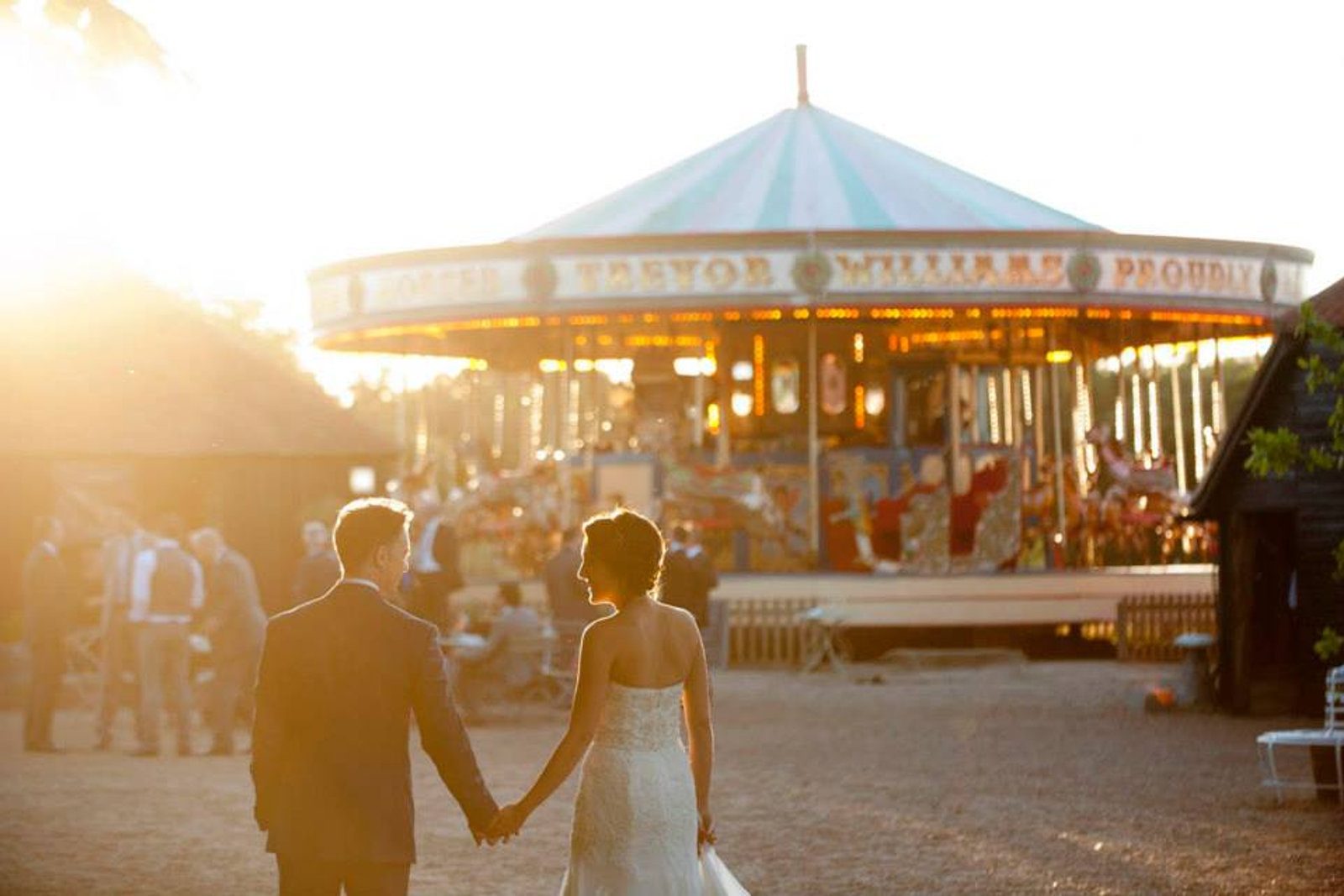 A couple hand in hand before the carousel at golden hour