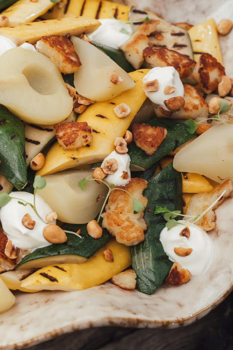 Pear salad with grilled vegetables and golden cheese on a cream platter