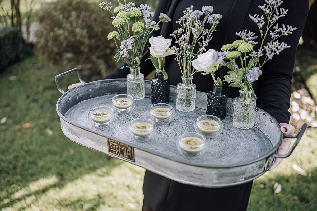 Canapés presented on a silver tray with a collection of flower-filled vases